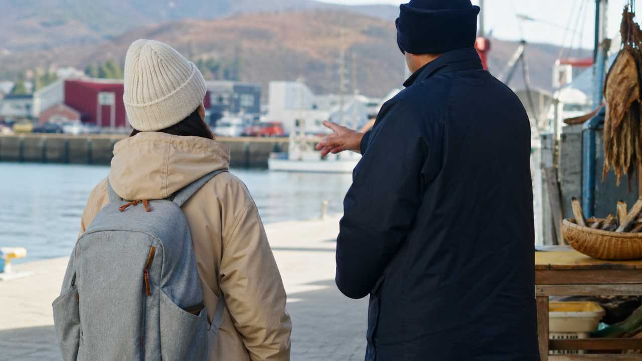 北海道旅行中に地元の人と会話している雰囲気、後ろ姿や手元中心、方言文化を感じる自然な写真