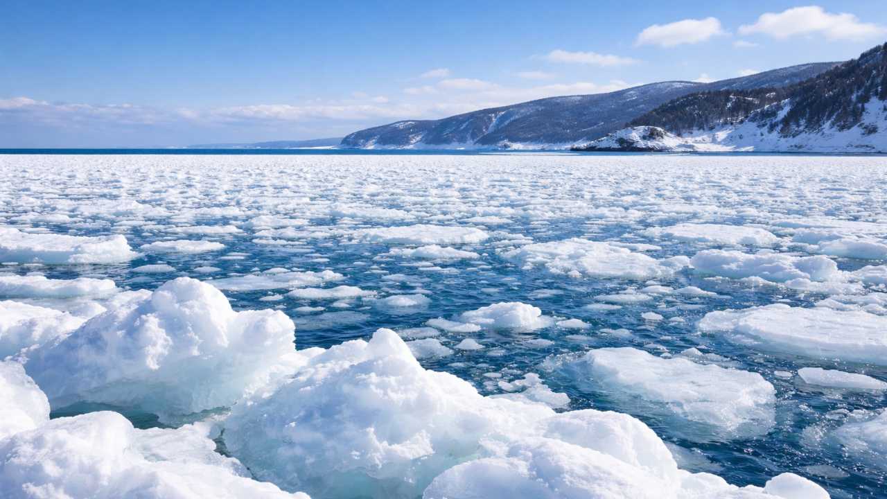 北海道のオホーツク海に広がる大規模な流氷原、冬の澄んだ青空、遠景に北海道らしい海岸線
