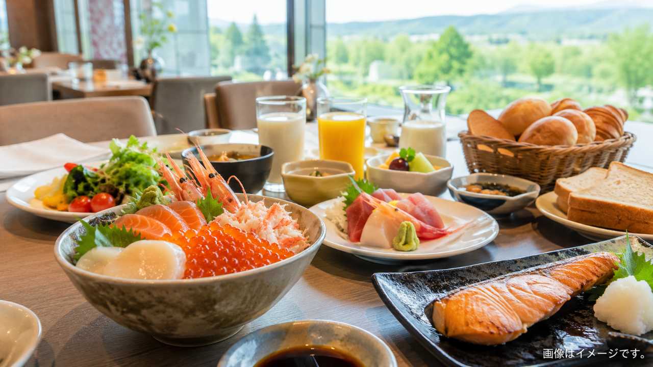 北海道のホテル朝食をテーマにしたブログ用アイキャッチ画像。明るい朝の自然光が入るホテルレストランで、海鮮丼、いくら、刺身、焼き魚、道産野菜、牛乳、パンが美しく並ぶ実写風写真