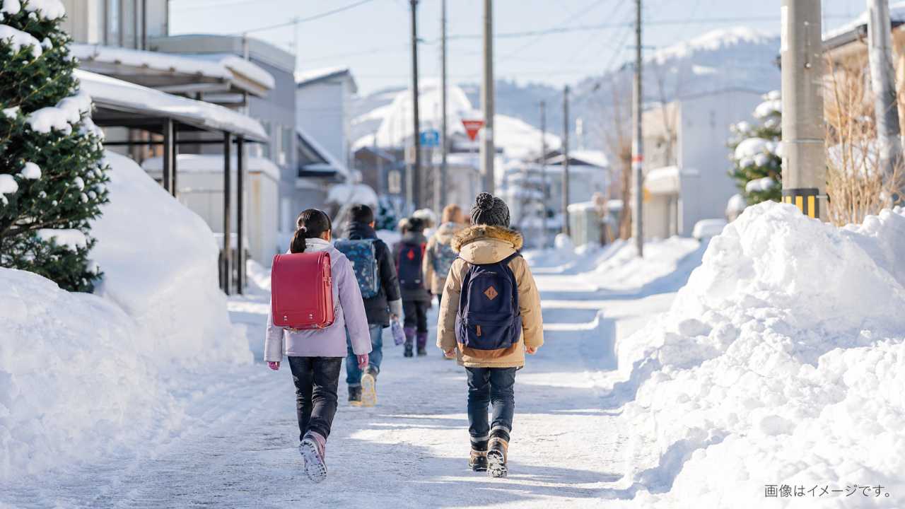 北海道の冬の住宅街で、小学生が雪道を安全に歩いて登校している実写風