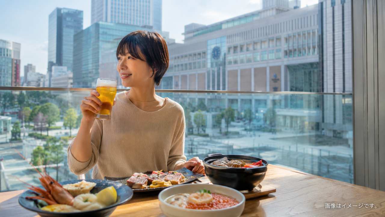 札幌駅周辺の昼の街並みを背景に、一人で気軽にビールと北海道グルメを楽しむ