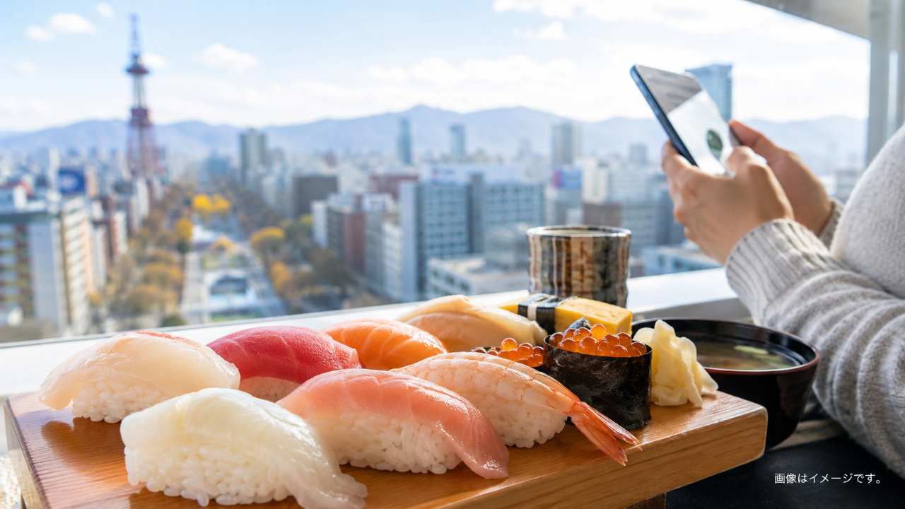 札幌の街並みを背景に、北海道らしい新鮮な寿司が並ぶ