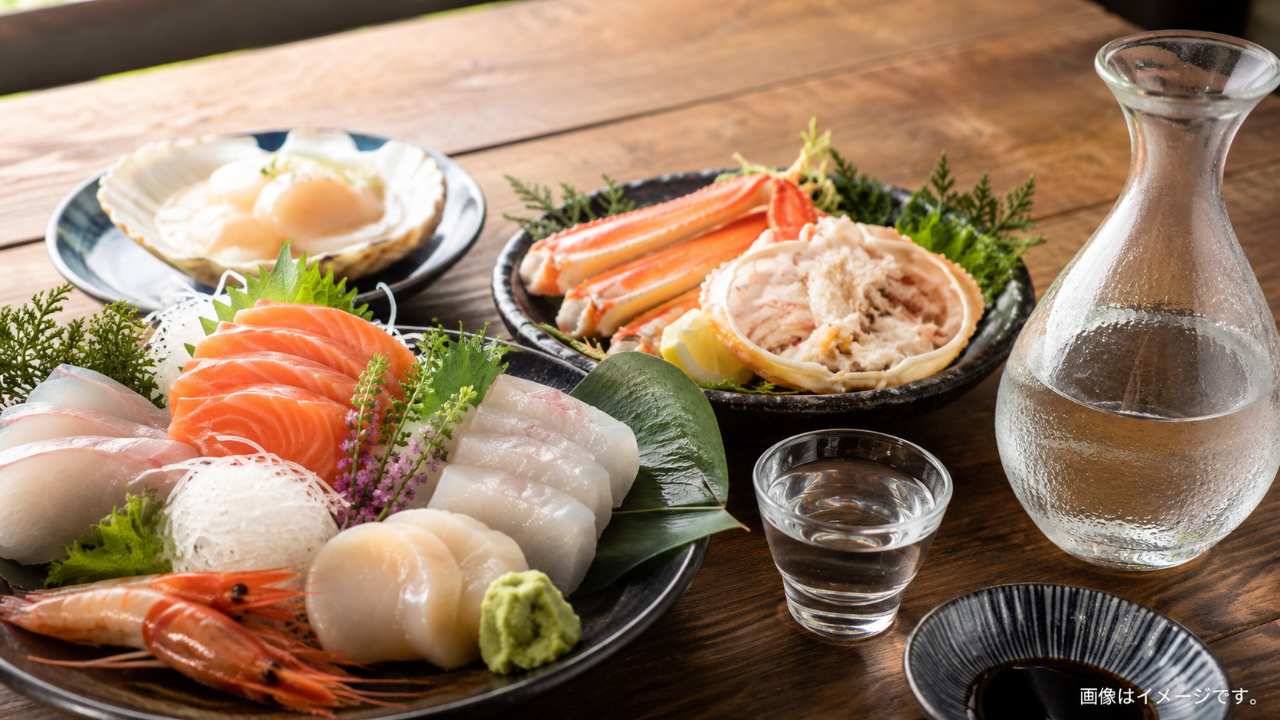 北海道の海鮮料理と日本酒のペアリング画像。刺身、ホタテ、カニ、鮭、日本酒グラスを木のテーブルに配置